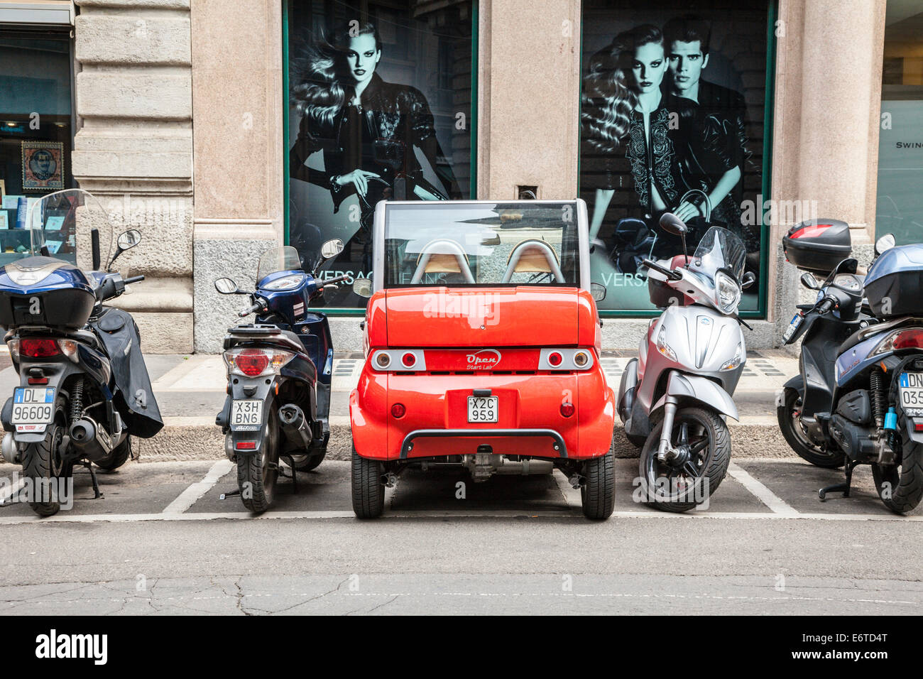 Small red electric car parked in a motorcycle parking area, Milan, Italy Stock Photo