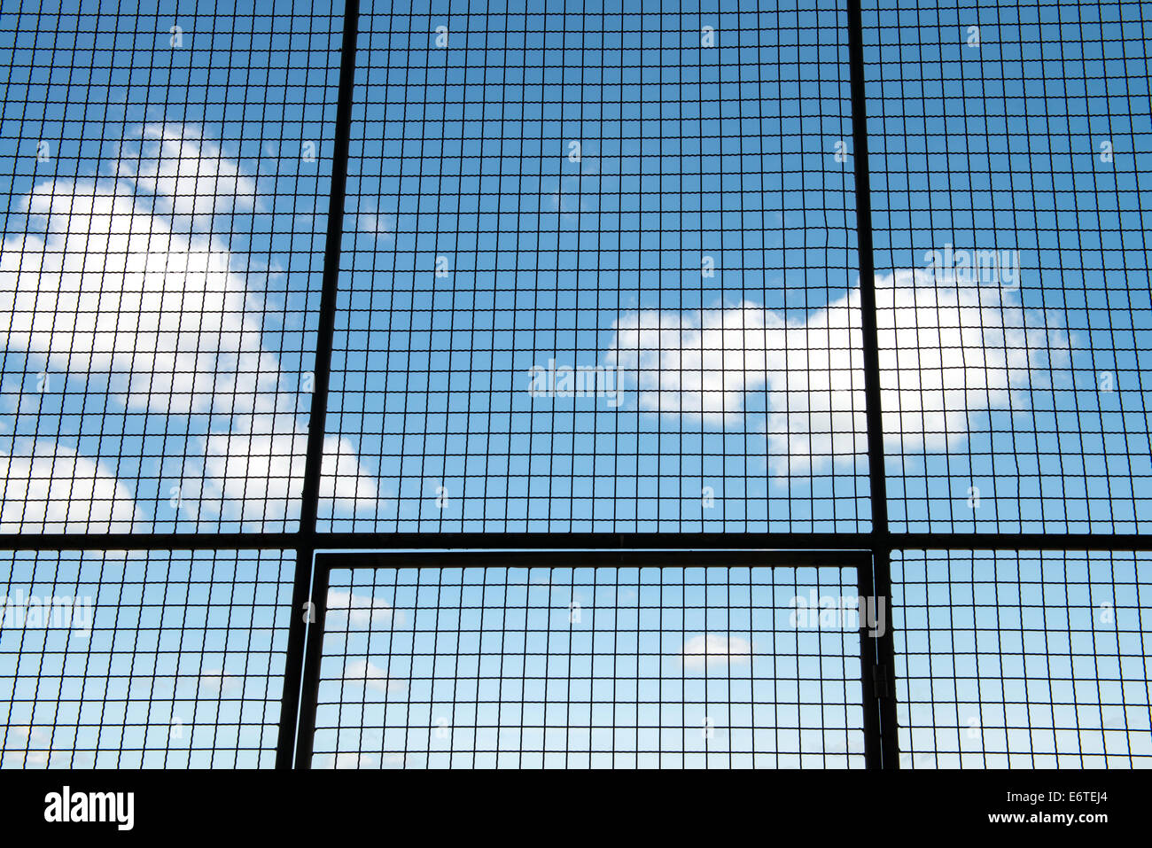 Metal mesh wire fence with blue sky and cloud background Stock Photo