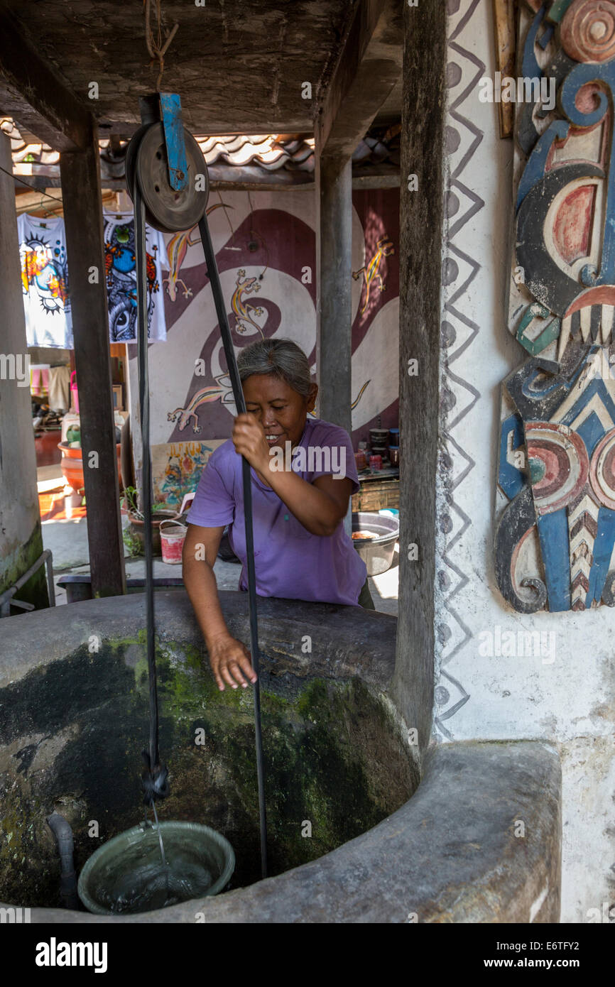 Yogyakarta, Java, Indonesia.  Woman Drawing Water from her Private Well in Neighborhood Family Home. Stock Photo