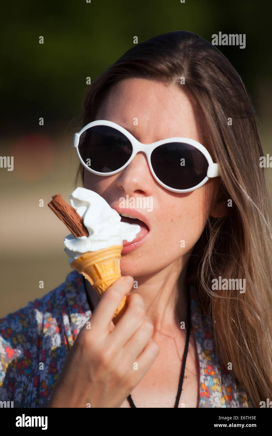 A young woman eating an ice cream in Hyde Park in Summer Stock Photo