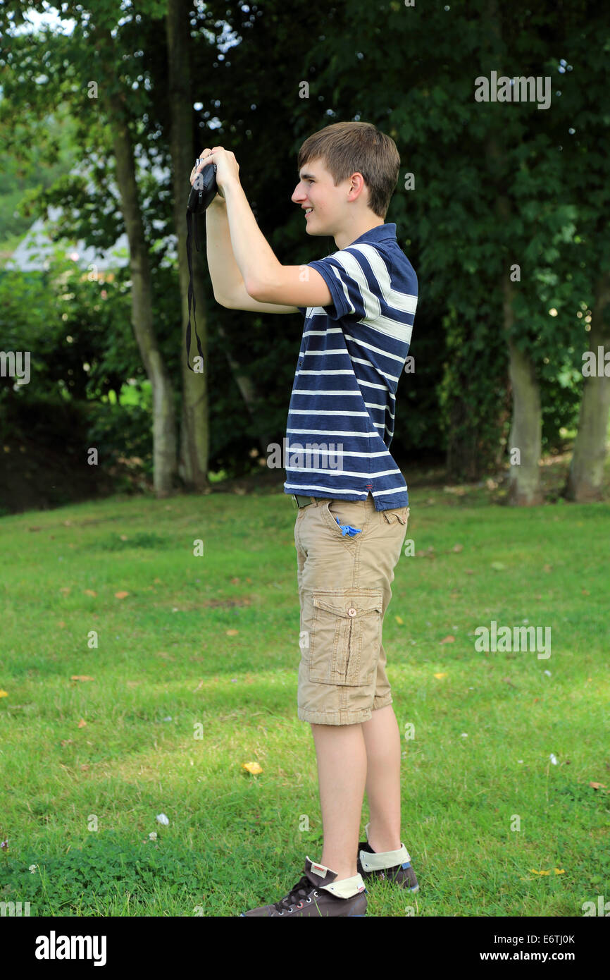 15 year old boy standing and photographing in park on Rue Rambour Panny, Illiers Combray, Centre