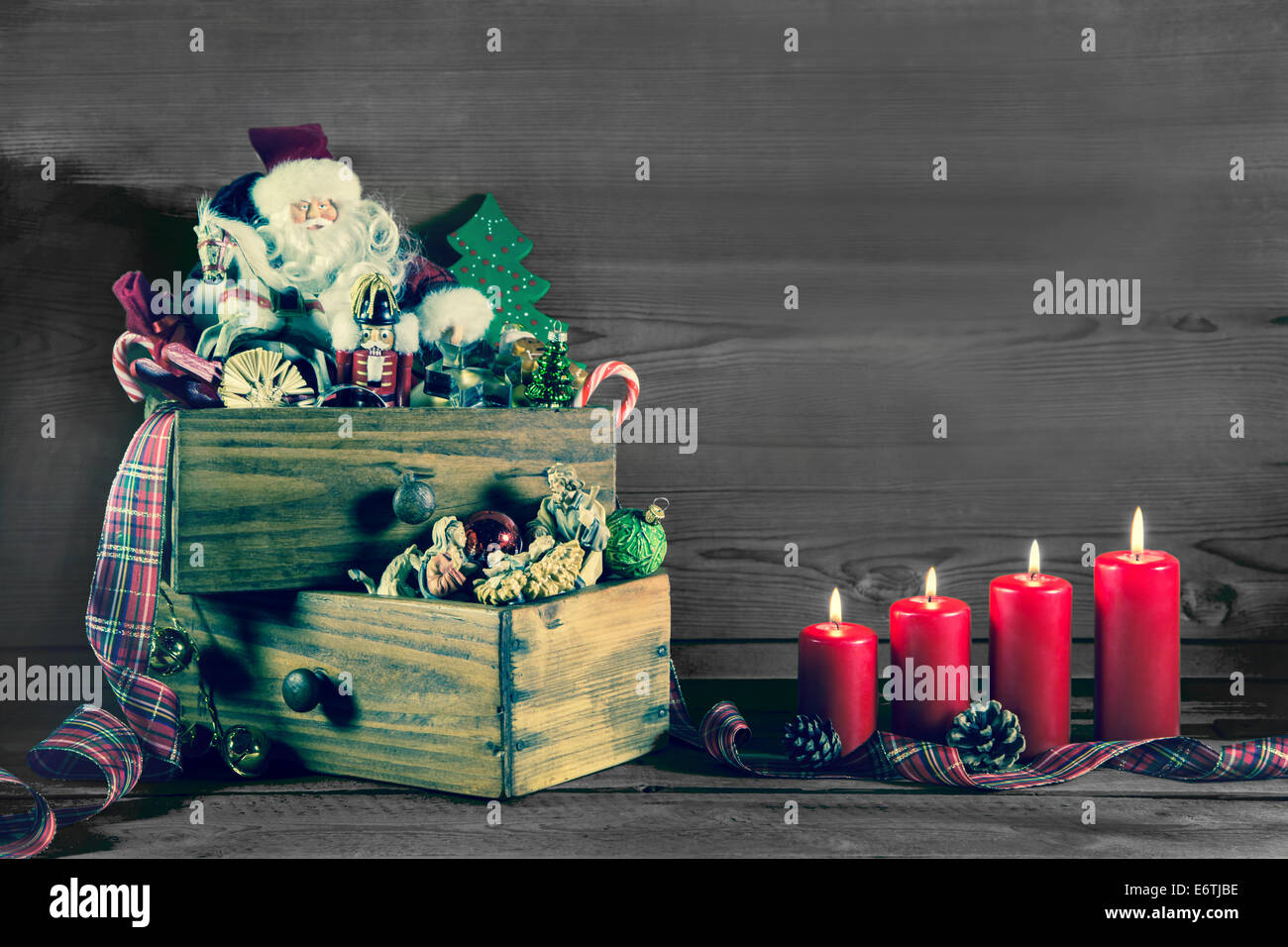 Four burning christmas candles with santa and old advent decoration on wood. Stock Photo