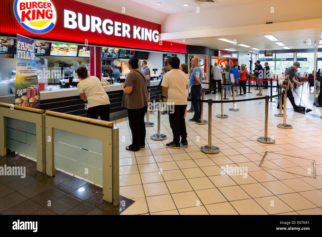 People queuing at Burger King in a motorway service station. Several large customers in the foreground. Stock Photo