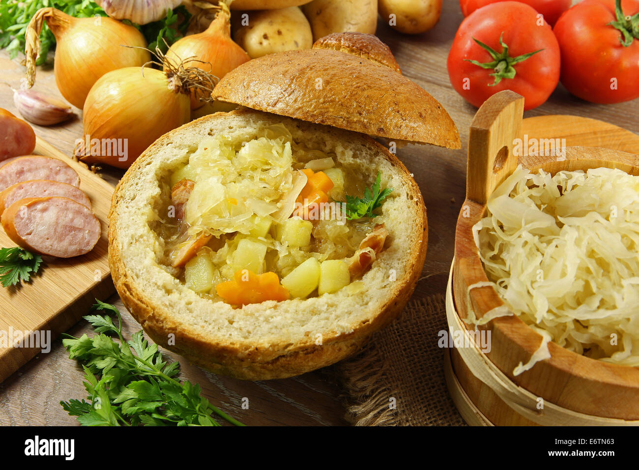 Cabbage soup in a loaf of bread and vegetables on a wooden table Stock