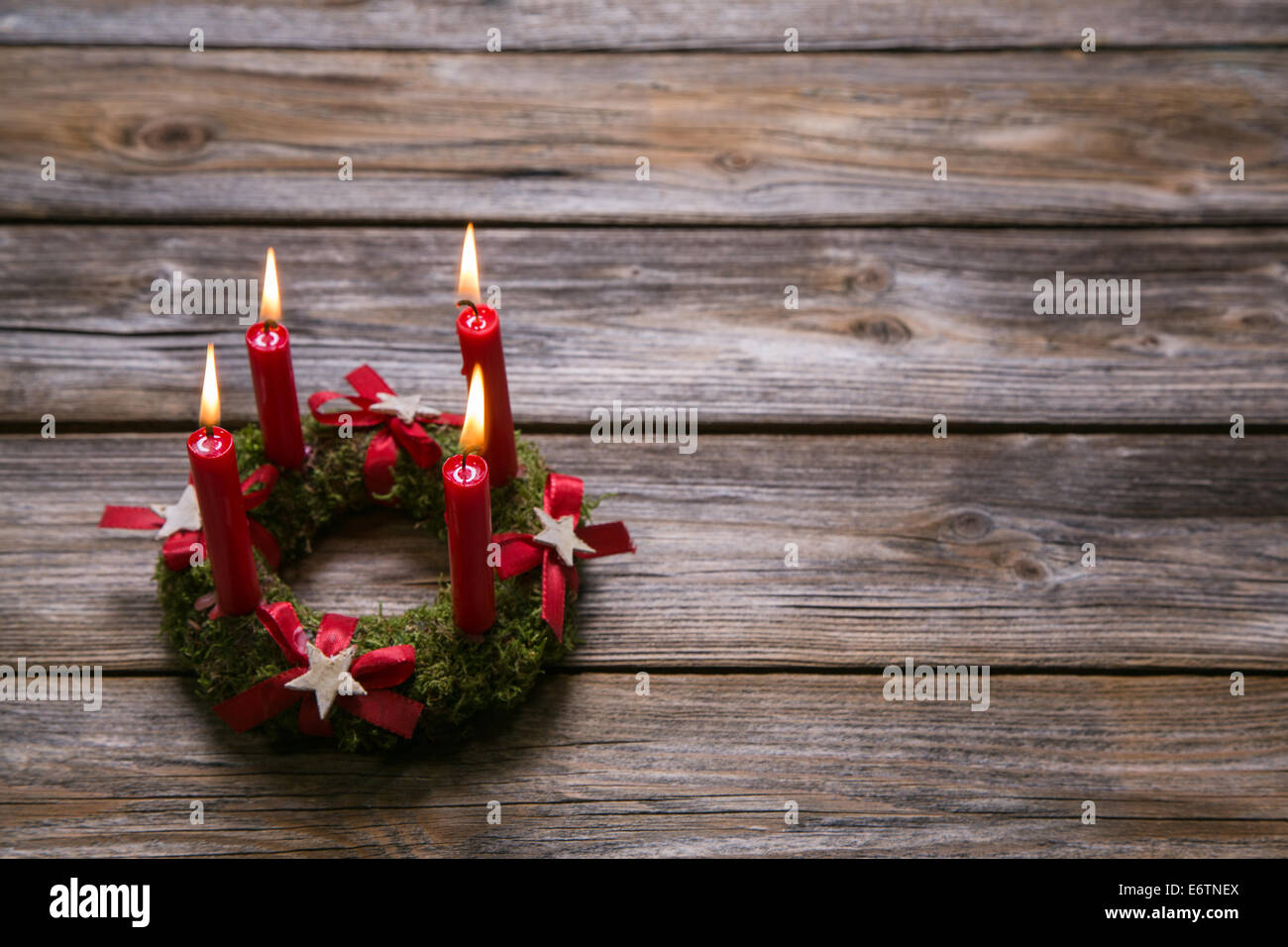 Natural advent wreath with four red candles on wooden old background. Stock Photo