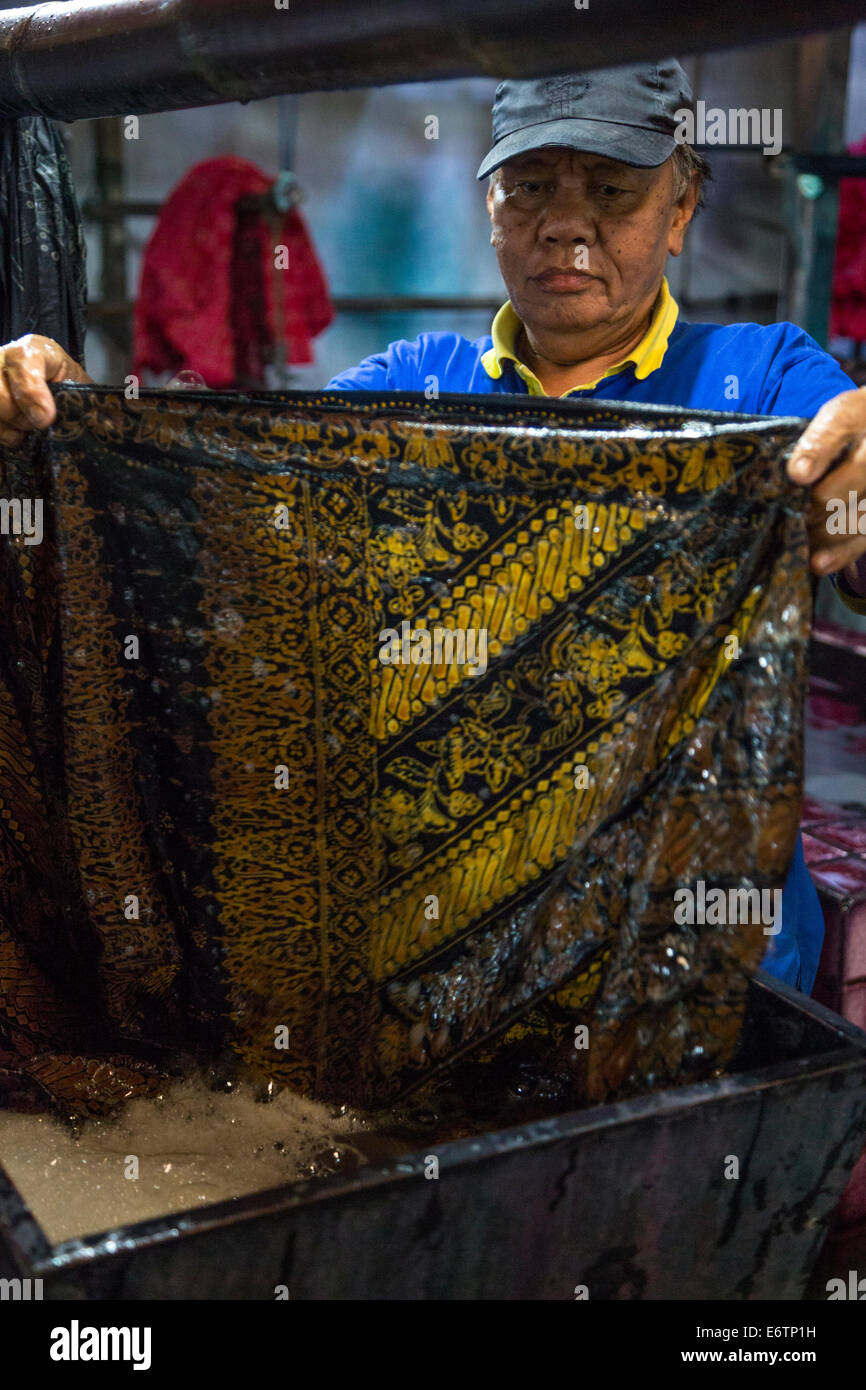 Yogyakarta, Java, Indonesia.  Batik Workshop.  Male Worker Examining Batik Cloth after Dying. Stock Photo