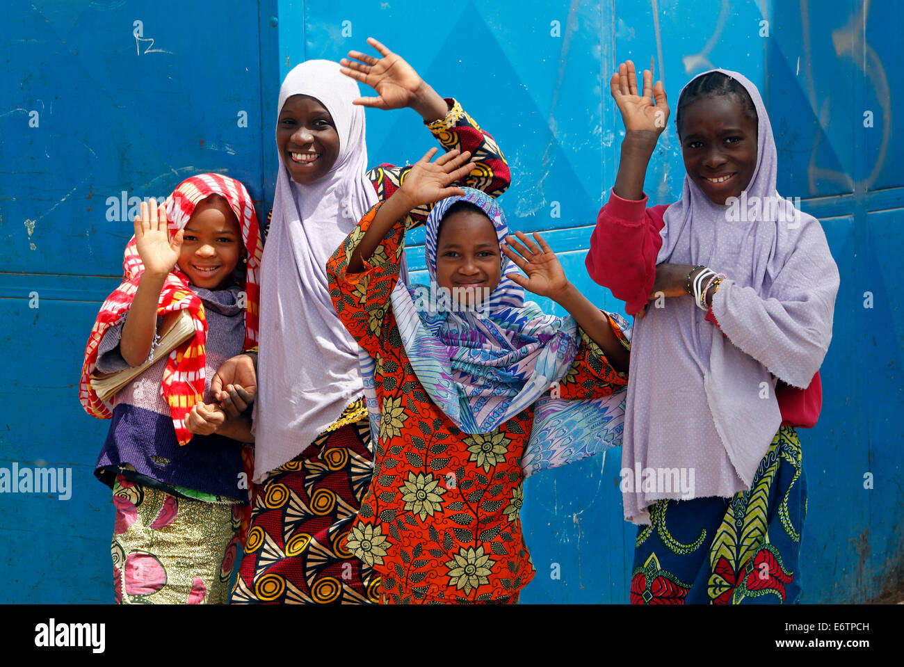 young girl wearing headscarfs, hijabs waving to the photographer. Dakar, Senegal Stock Photo