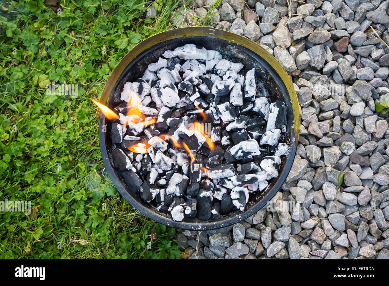 Portable camping barbecue lit on the floor Stock Photo