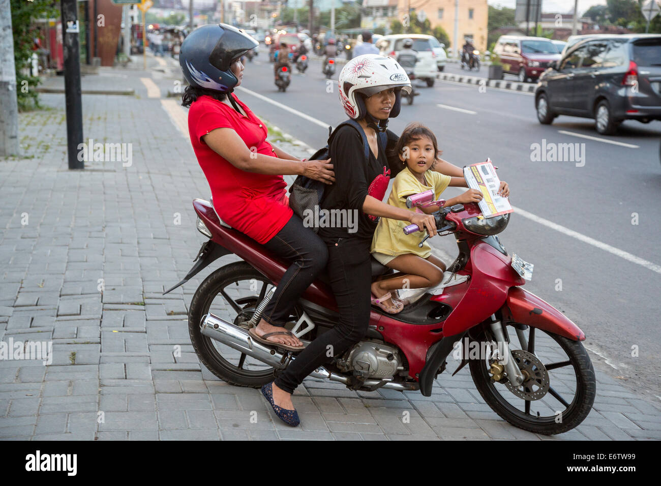 Yogyakarta, Java, Indonesia.  Two Women and Little Girl on Motorbike  about to Enter Evening Traffic, Jl. Laksda Adisucipto St. Stock Photo