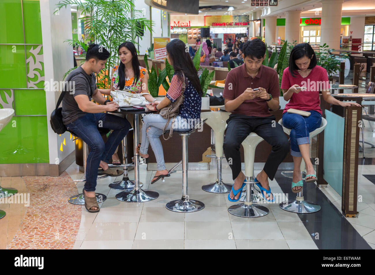 Yogyakarta, Java, Indonesia.  Ambarrukmo Shopping Mall.  Two Young Couples and a Friend in the Food Court. Stock Photo