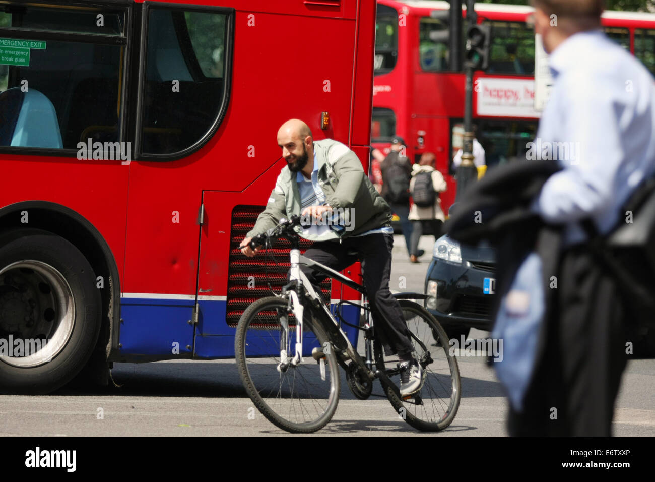 A cyclist riding around a roundabout alongside a bus, in London Stock ...