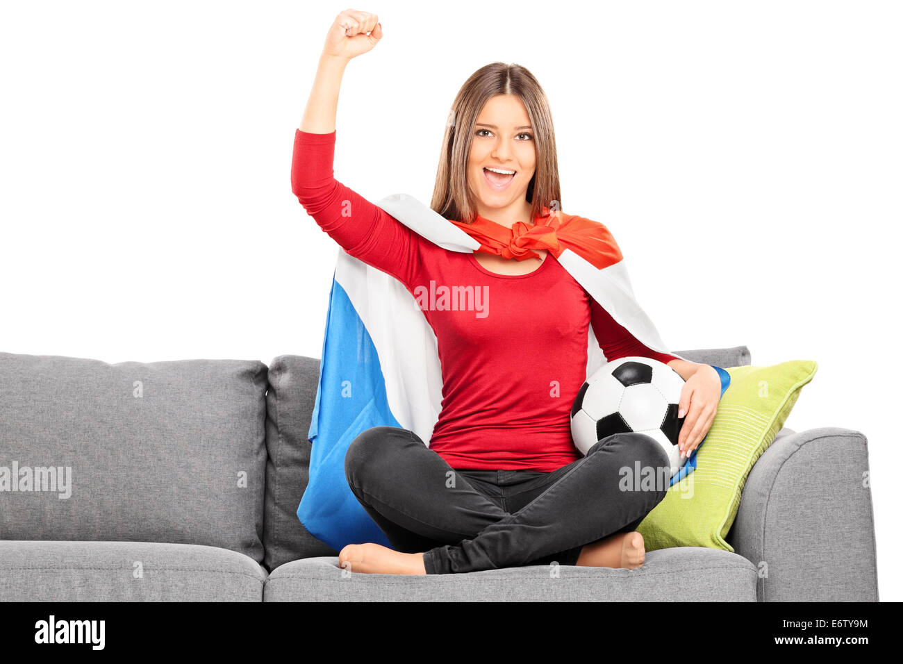 Female sport fan cheering seated on a couch isolated on white