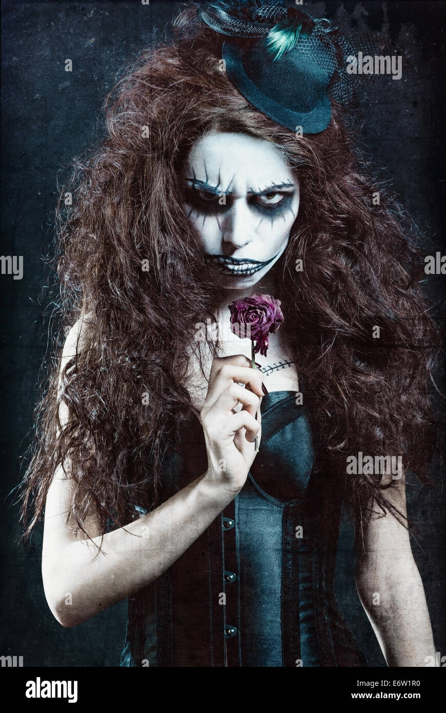 Woman in image of a gothic freak clown with withered flower. Grunge texture effect Stock Photo
