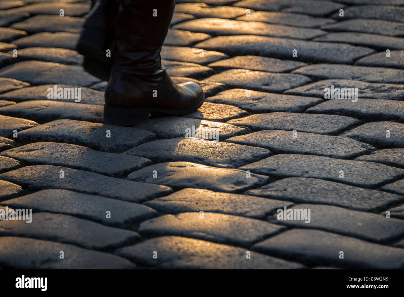 Person hurrying home over cobbles at dusk Stock Photo