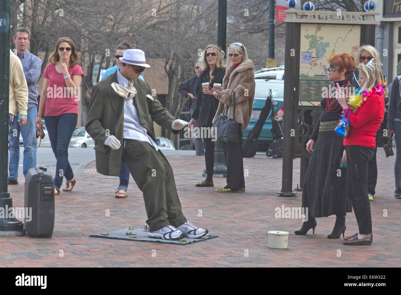 Asheville, North Carolina, USA - March 2, 2014: Living statue street artist showing a man in a suit being blown backward Stock Photo