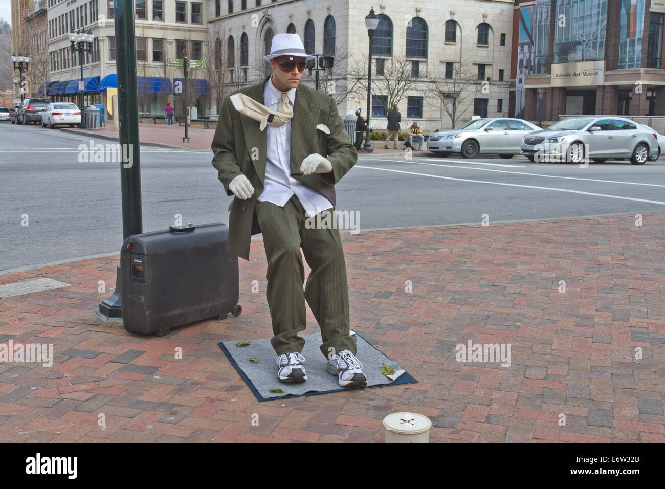 Asheville, North Carolina, USA - March 2, 2014: Living statue performance street artist showing a man in a suit being blown back Stock Photo