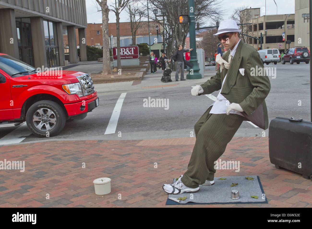 Asheville, North Carolina, USA - March 2, 2014: Living statue street artist showing a man in a suit being blown back a an angle Stock Photo
