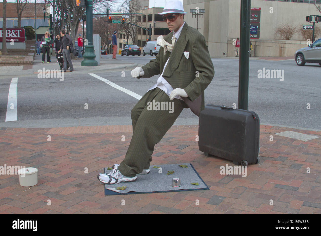 Male living statue street busker performs for tips wearing a suit and leaning at an impossible angle in downtown Asheville, NC Stock Photo