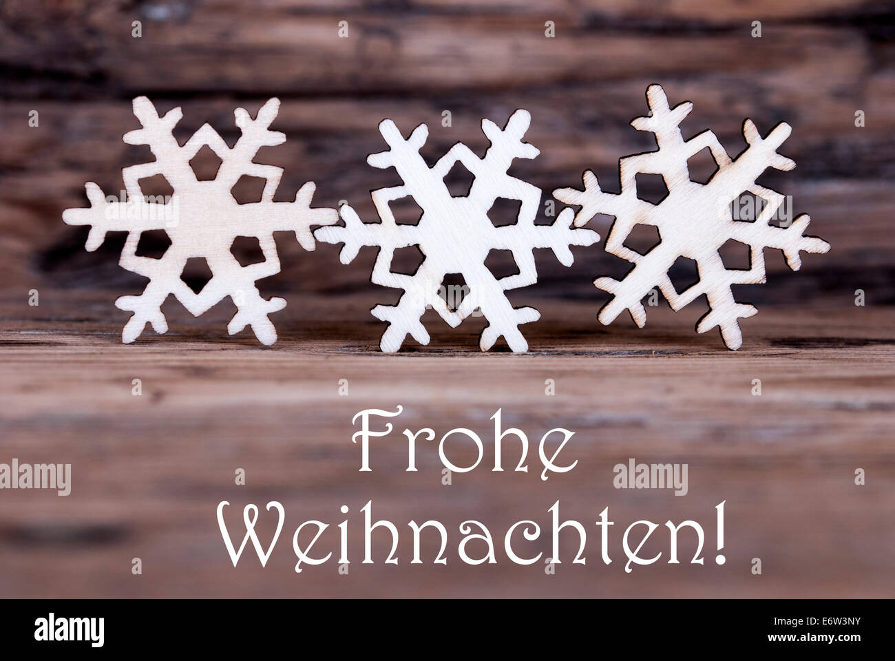 Three Wooden Snowflakes with the German Words Frohe Weihnachten which means Merry Christmas Stock Photo