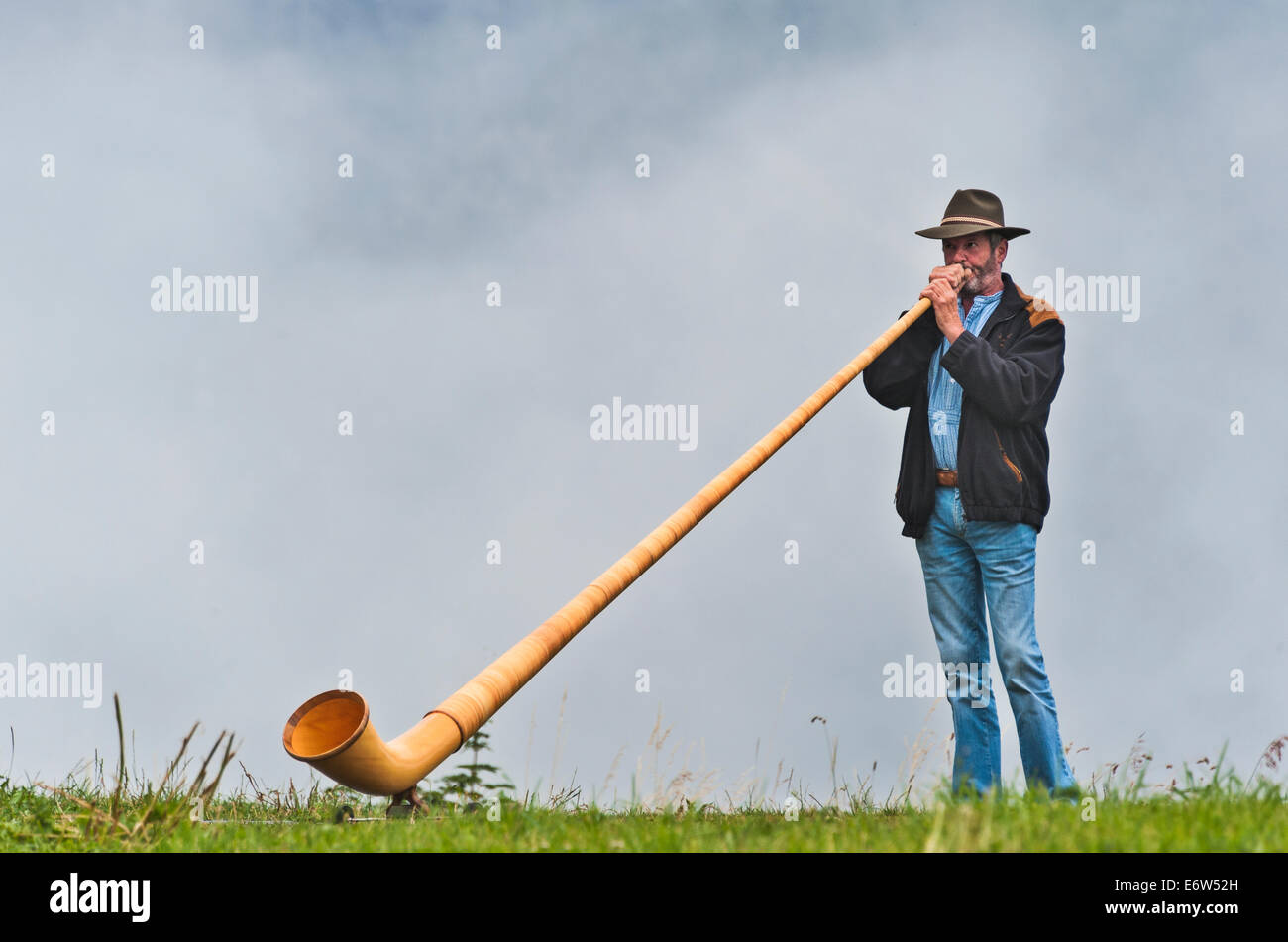an-alphorn-player-playing-his-instrument-on-a-ridge-above-the-alpine-E6W52H.jpg