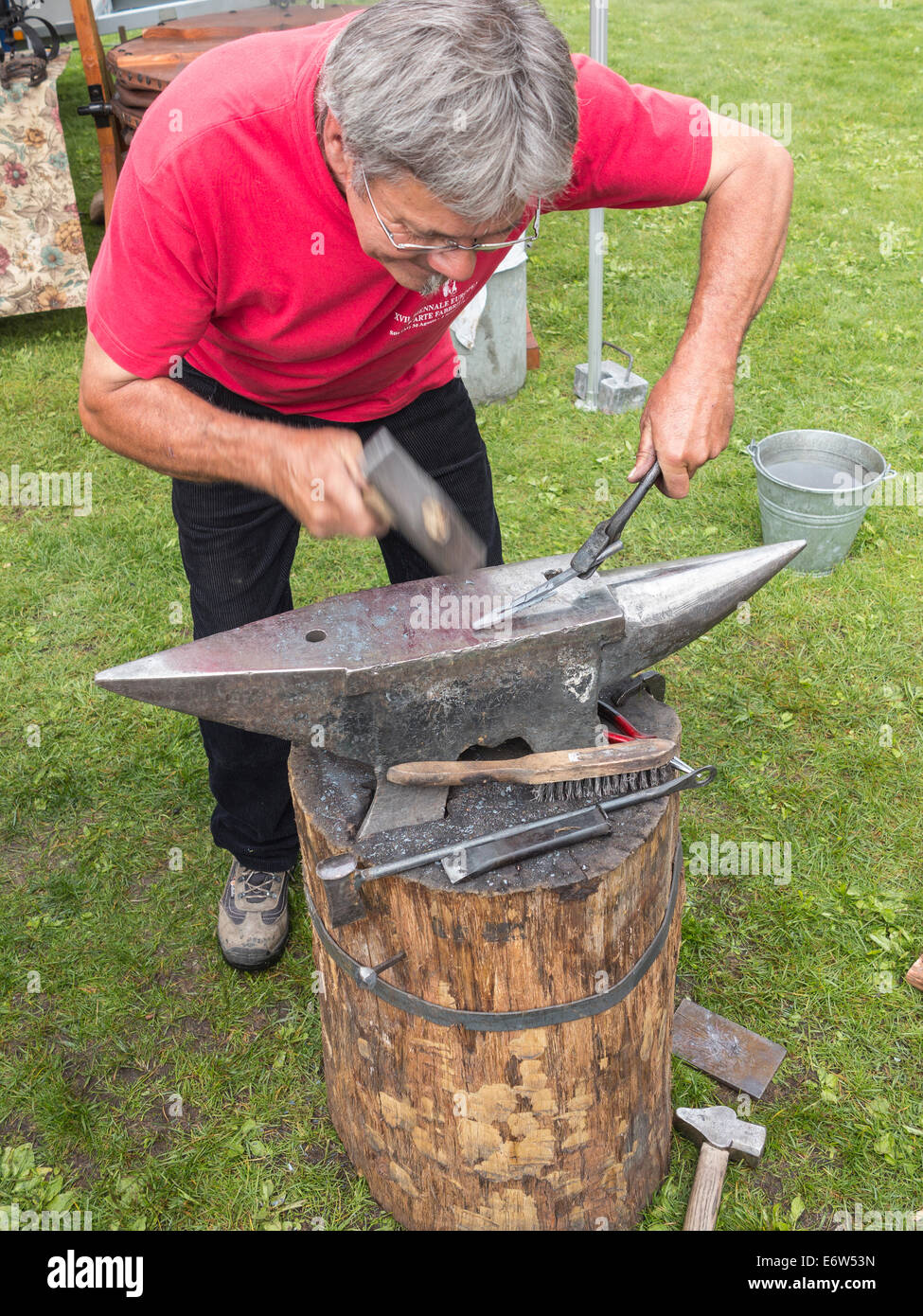 A blacksmith hammering a piece of hot iron into shape on an anvil Stock Photo