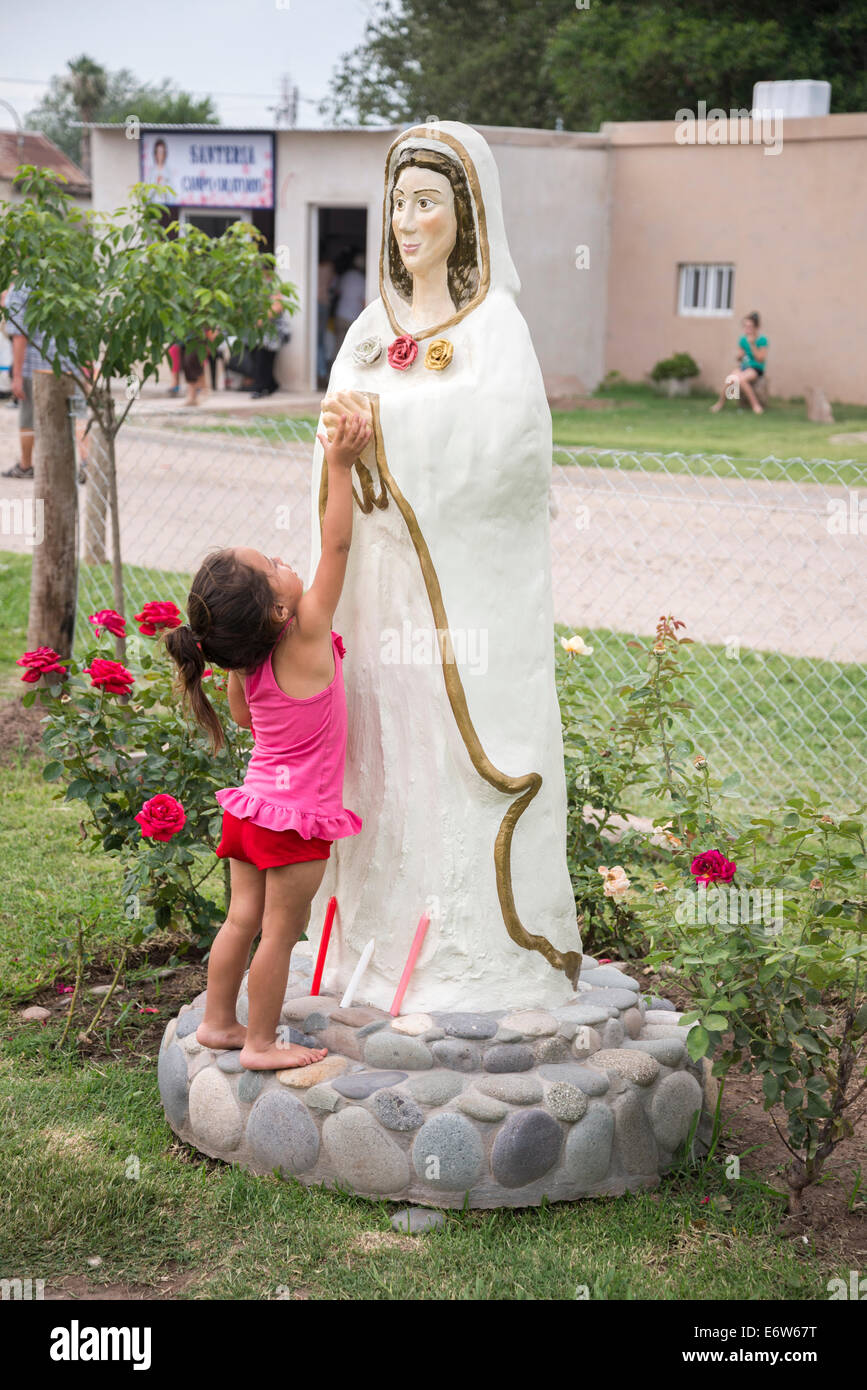 CENTENO, SANTA FE, ARGENTINA - DECEMBER 8, 2013: A child touches a statue of Mary the Mystical Rose in a prayer field Stock Photo