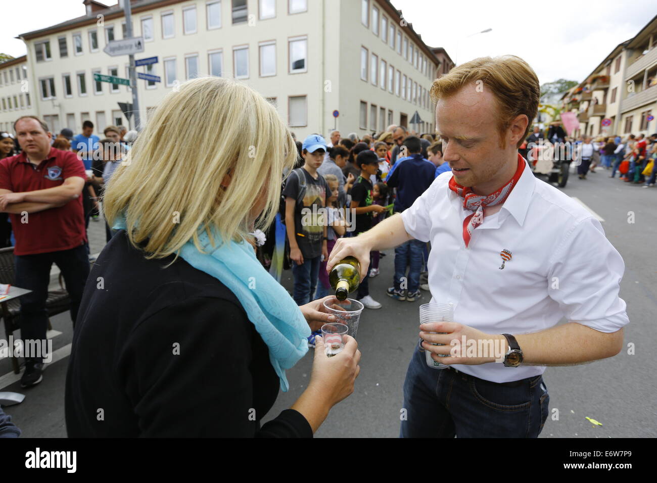 Worms, Germany. 31st Aug, 2014. Jan Metzler, the local MdB (member of the German parliament) from the conservative CDU, pours wine to a visitor at the the Backfischfest parade 2014. The first highlight of this year's Backfischfest was the big parade through the city of Worms with 125 groups and floats. Community groups, sport clubs, music groups and business from Worms and further afield took part. © Michael Debets/Pacific Press/Alamy Live News Stock Photo