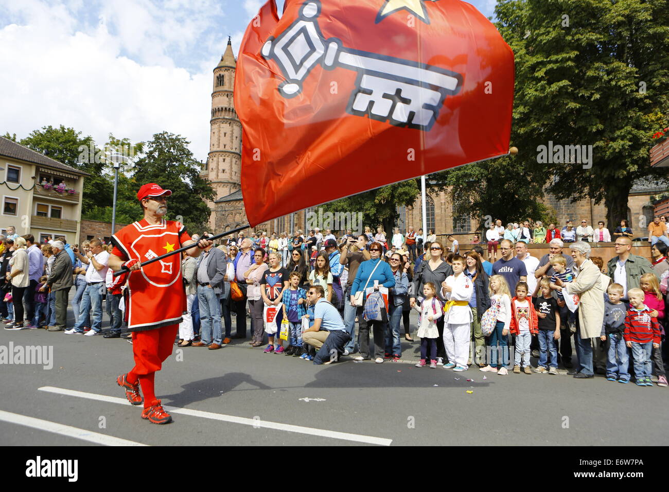Worms, Germany. 31st Aug, 2014. A color guard with a red flag with the coat of arms of Worms marches in the Backfischfest parade 2014. The cathedral of Worms can be seen in the background. The first highlight of this year's Backfischfest was the big parade through the city of Worms with 125 groups and floats. Community groups, sport clubs, music groups and business from Worms and further afield took part. © Michael Debets/Pacific Press/Alamy Live News Stock Photo
