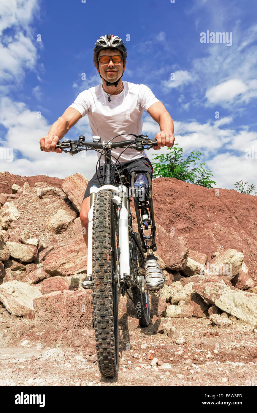 Shot of young male mountain bike rider with leg prosthesis between rocks. Stock Photo