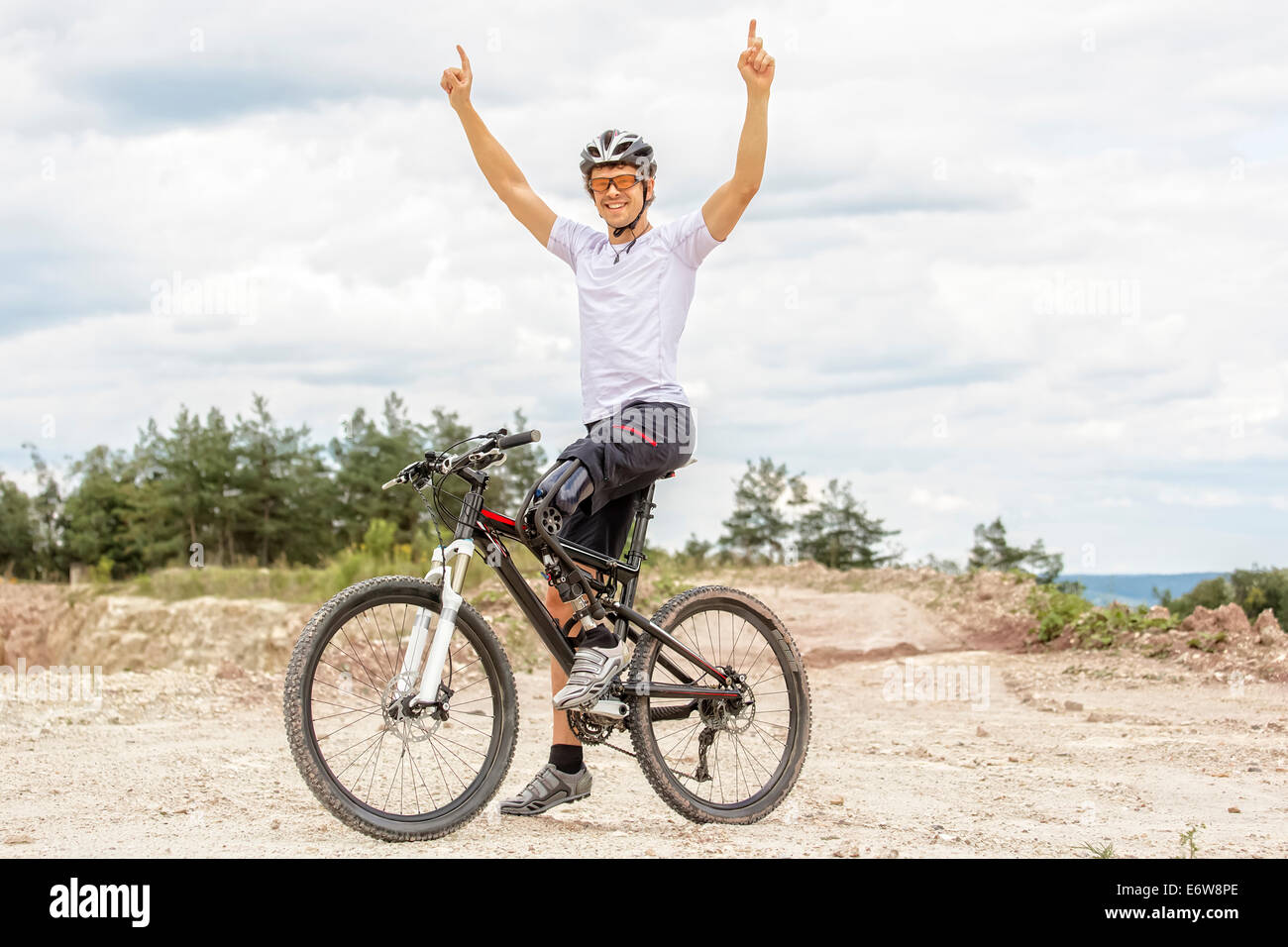 Shot of young  mountain bike rider with leg prosthesis raising up his arms Stock Photo