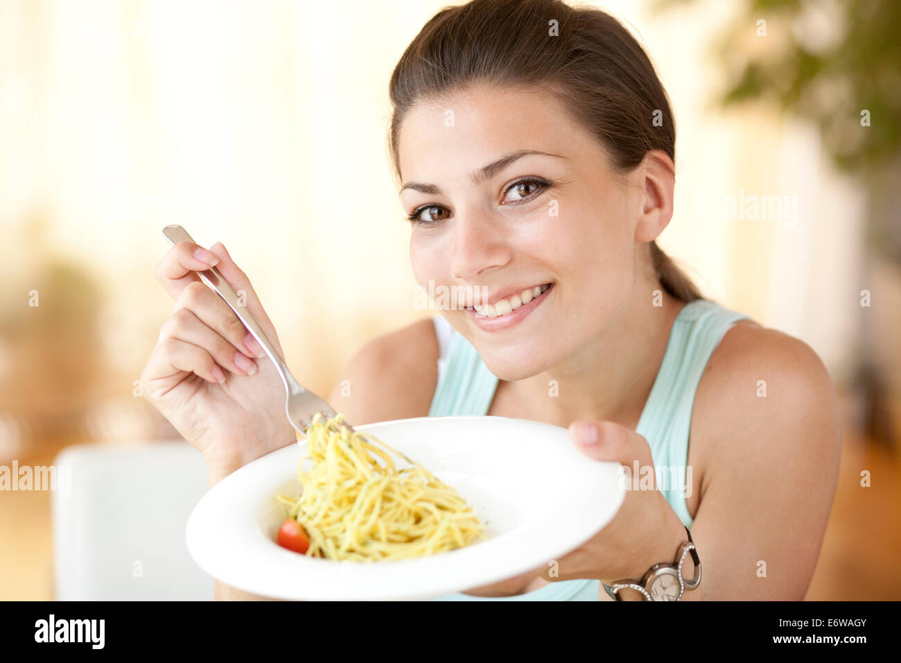 Young happy woman eating italian pasta with tomatoes, parmezan and basil. Stock Photo
