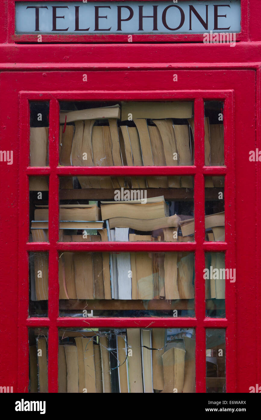 An old red telephone box finds new life as a local village library. Stock Photo