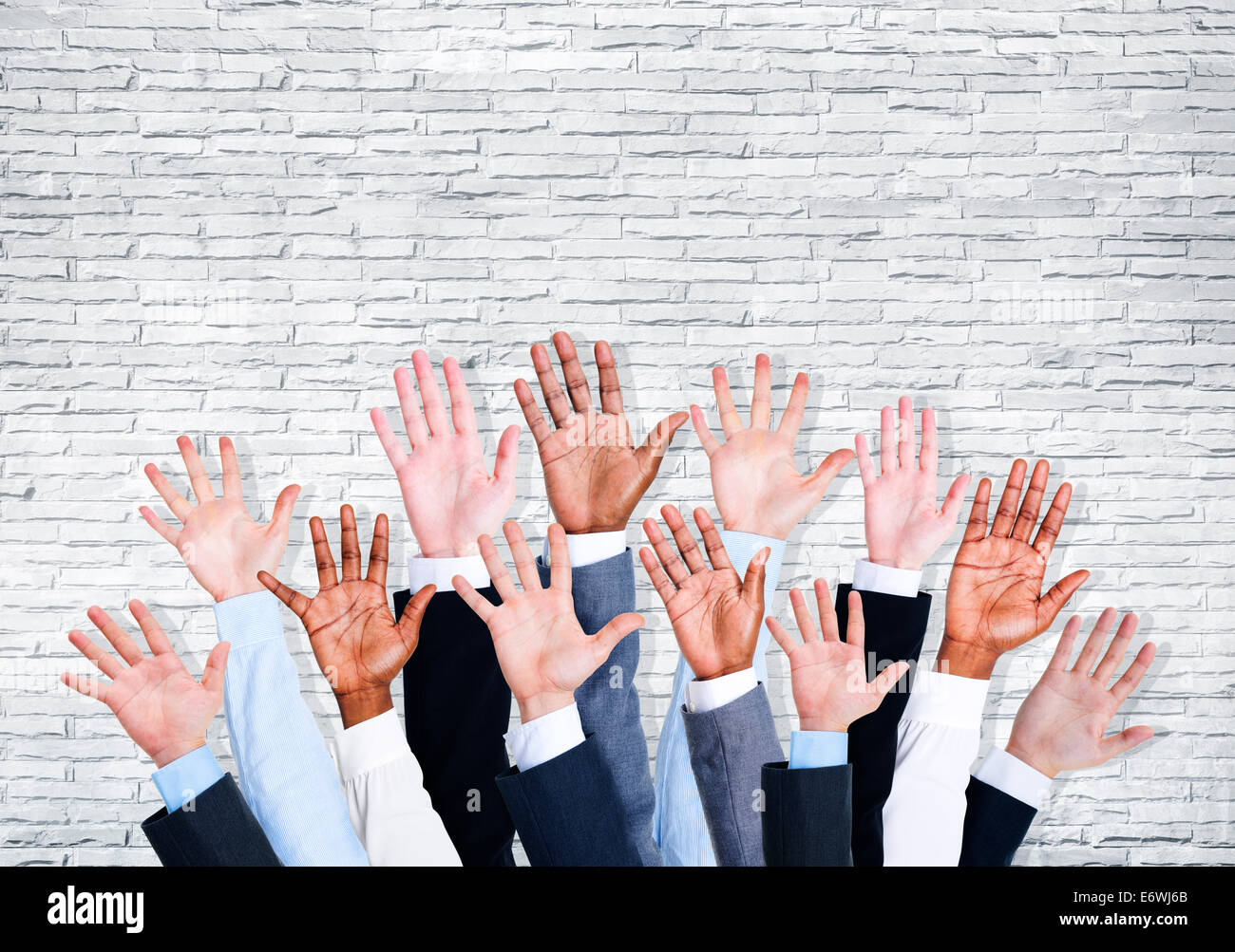 Group of business human arms raised with brick wall. Stock Photo