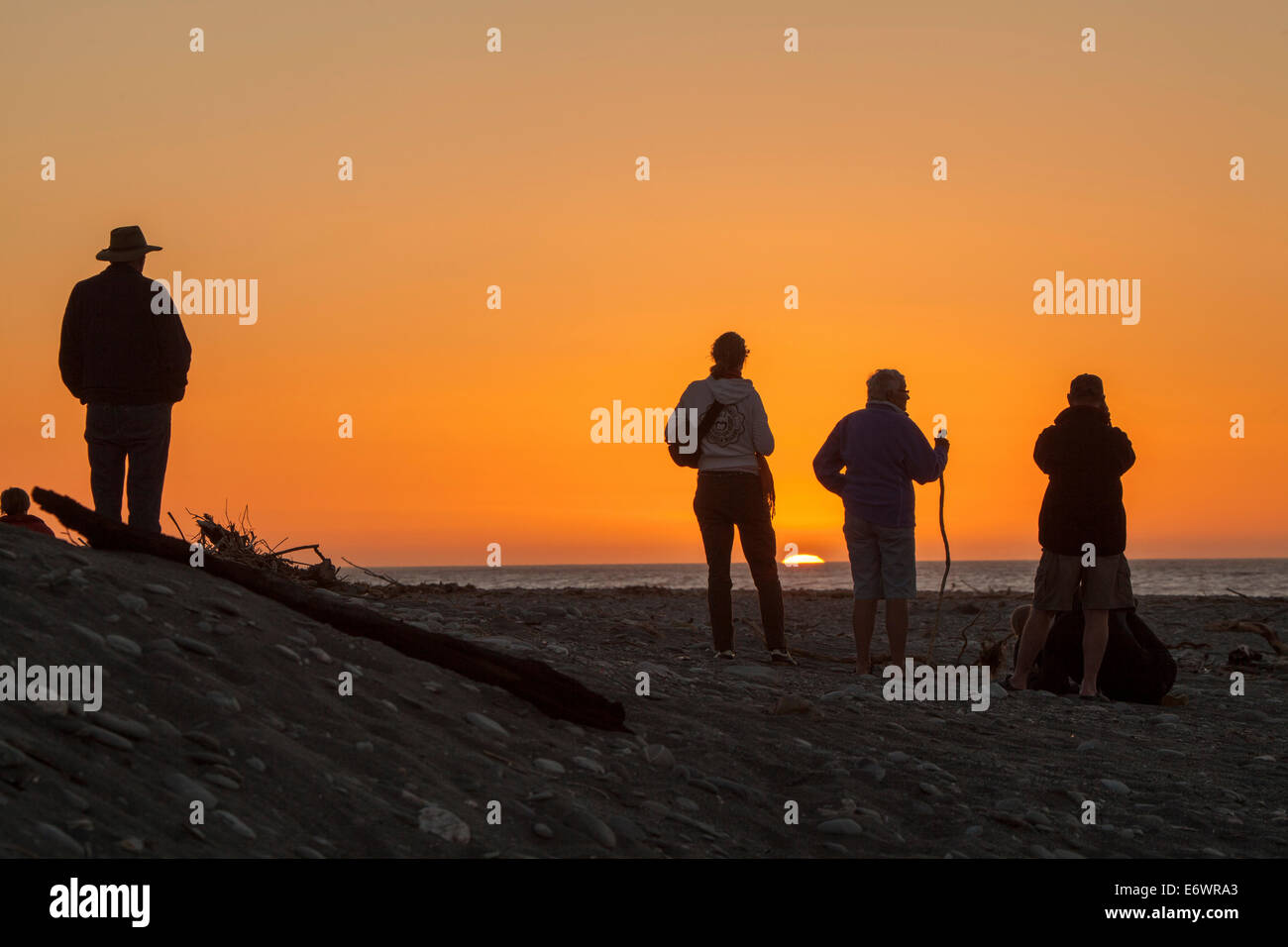 People watching the sunset on the beach, silhouettes, South Island, New Zealand Stock Photo