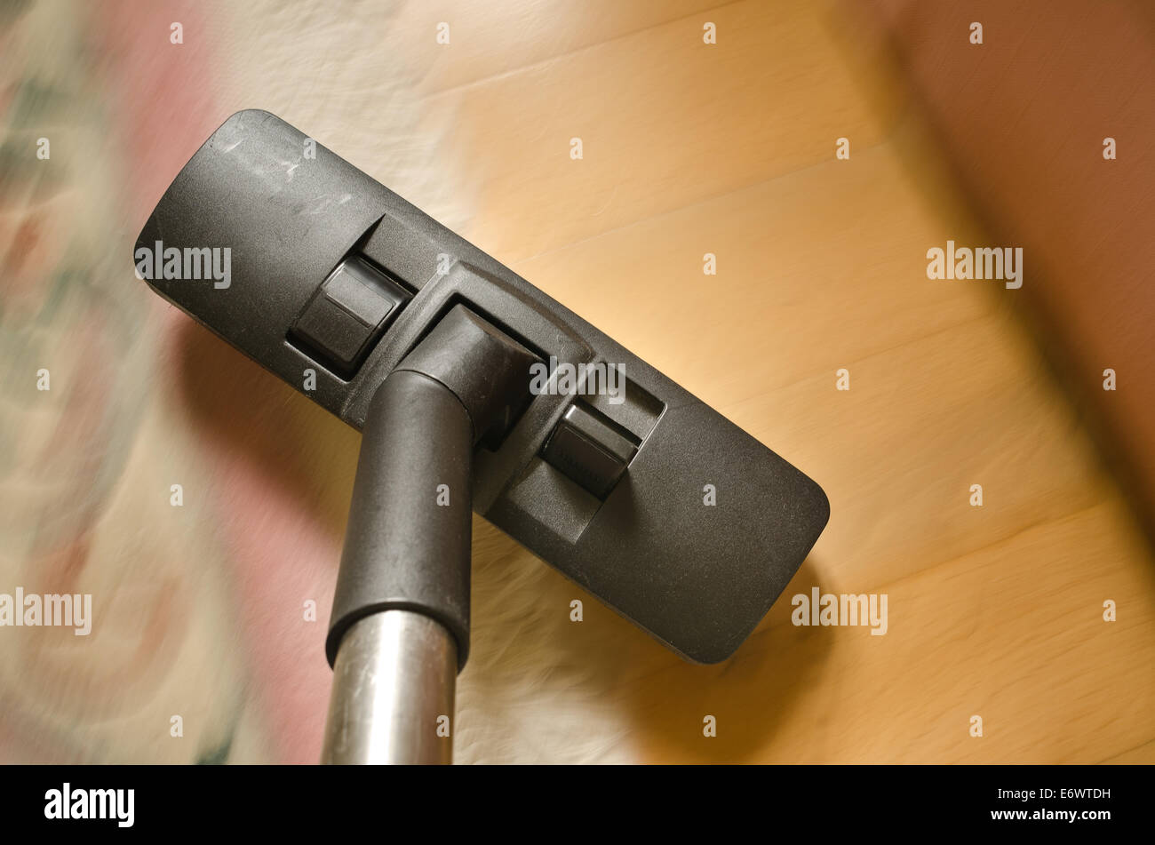 rush action and movement detailed view of hover nozzle being swept over carpets tiles wooden floor cleaning up dirt and dust Stock Photo