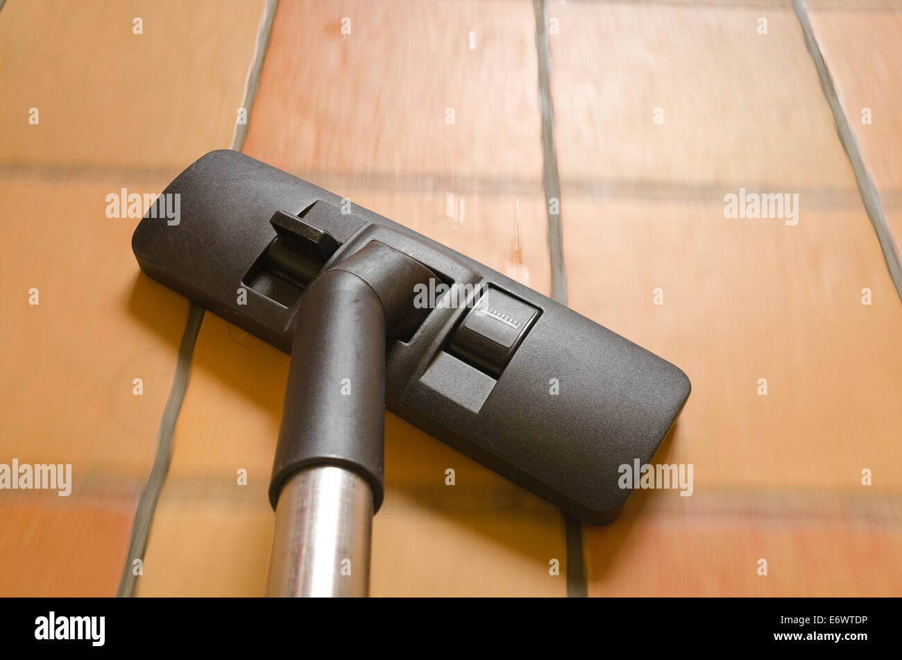 rush action and movement detailed view of hover nozzle being swept over carpets tiles wooden floor cleaning up dirt and dust Stock Photo