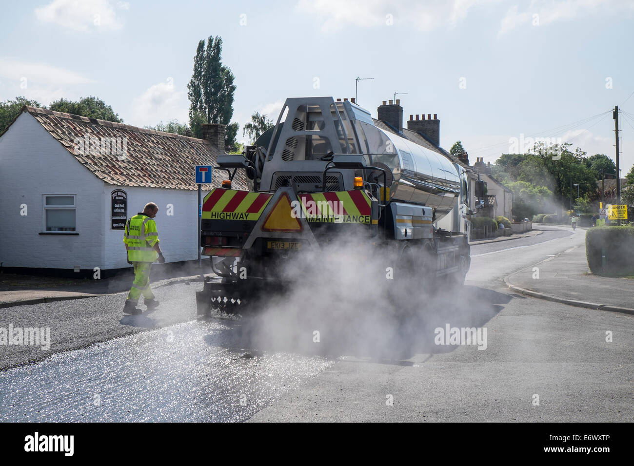 Road tar tanker spreading hot tar to take chippings Fen Road Milton Stock Photo