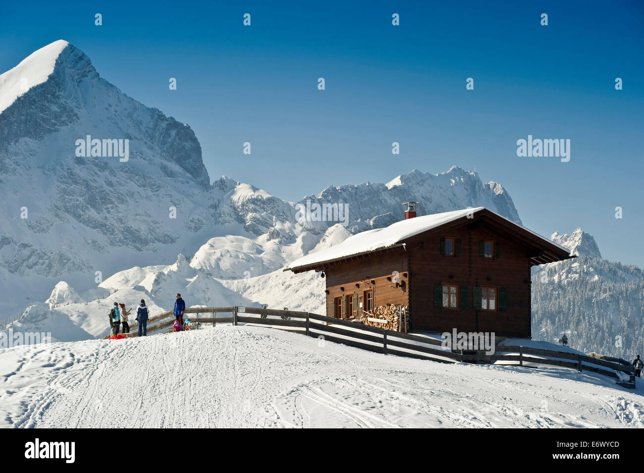 People sledging at Eckbauer, Alpspitze and Zugspitze in the background, Garmisch-Partenkirchen, Bavaria, Germany Stock Photo