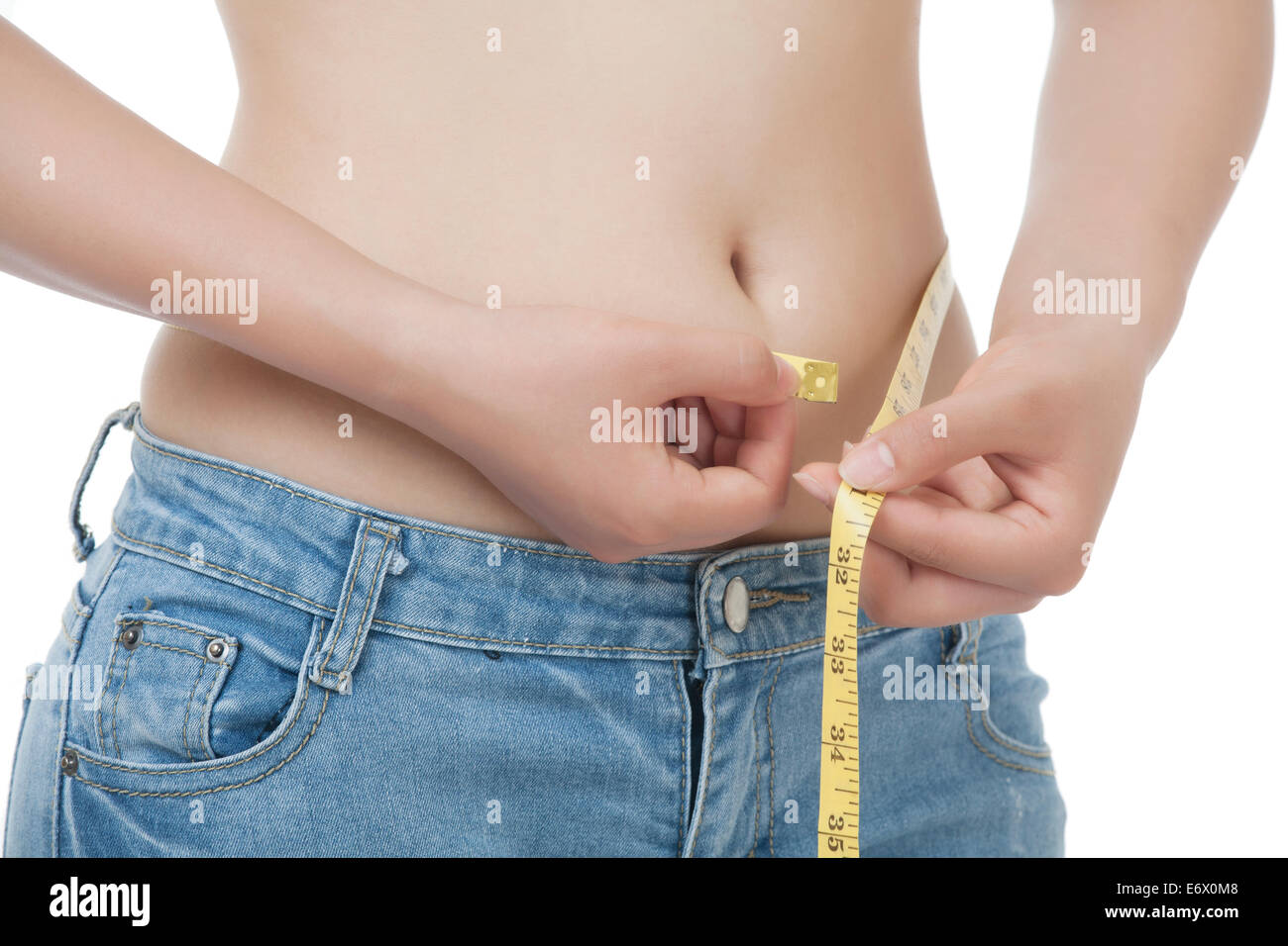 A very fit Asian woman measuring her waist isolated on a white background Stock Photo
