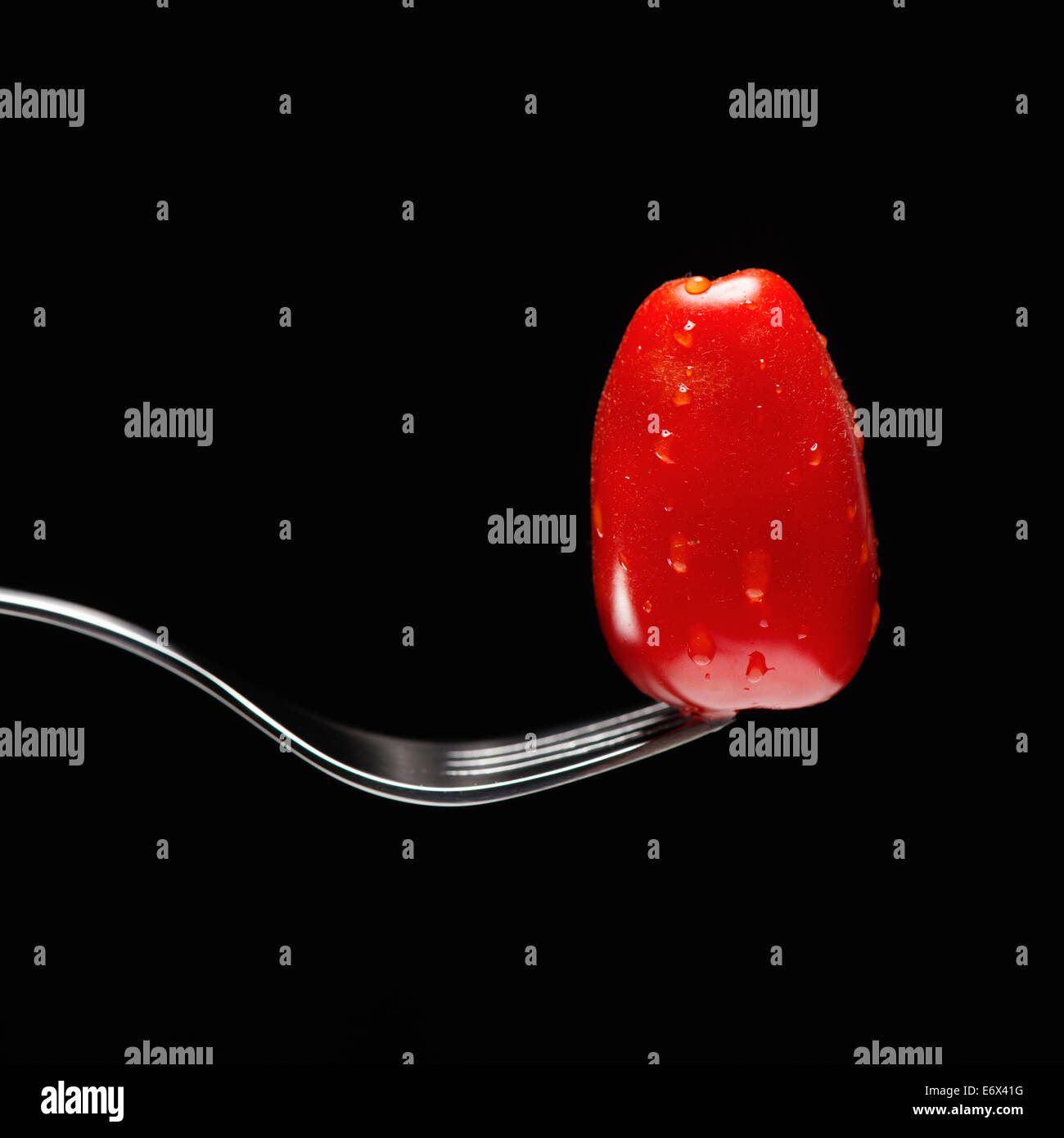 Still life of tomato balancing on end of fork Stock Photo