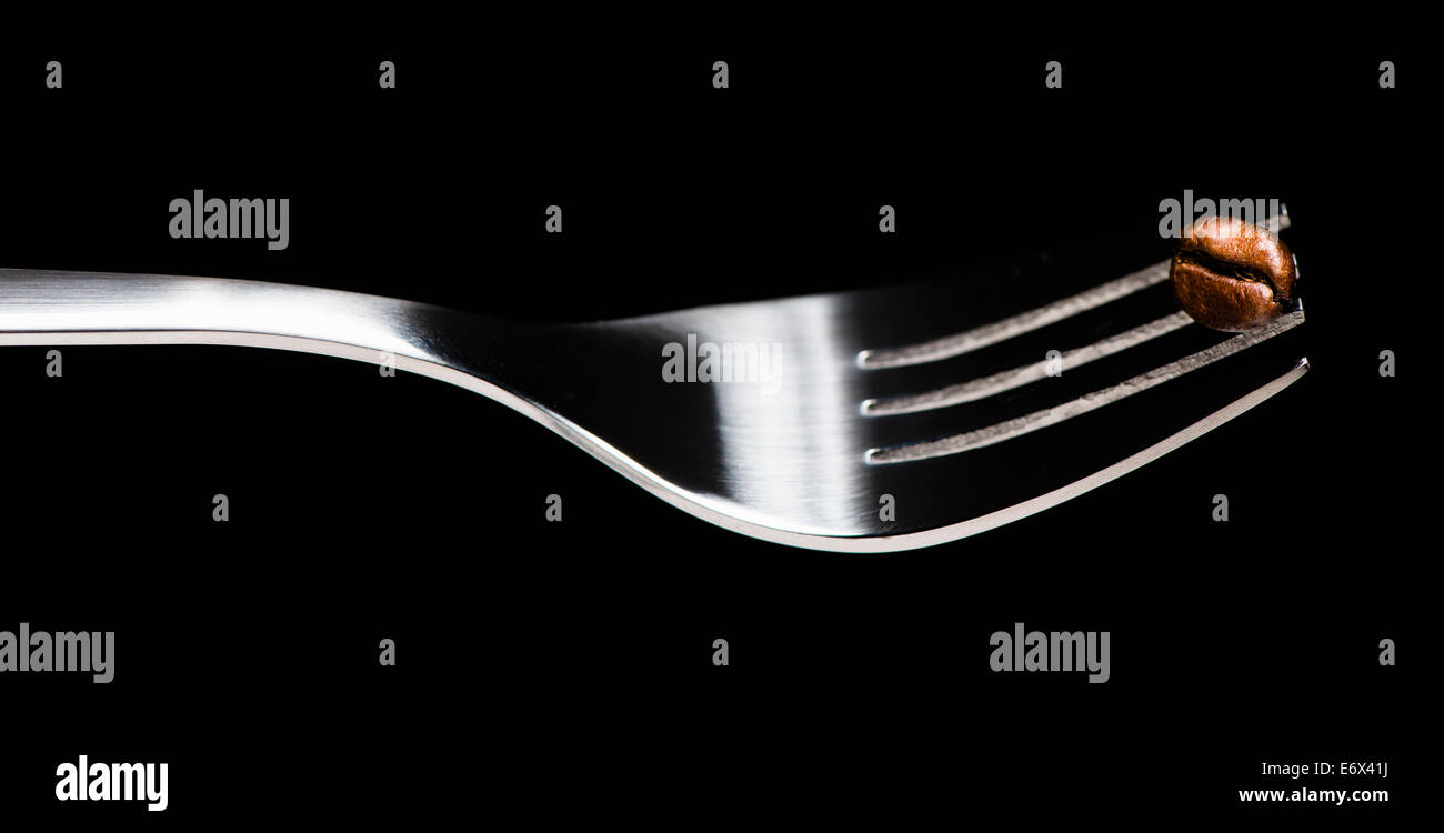 Still life of fork and one coffee bean. Stock Photo