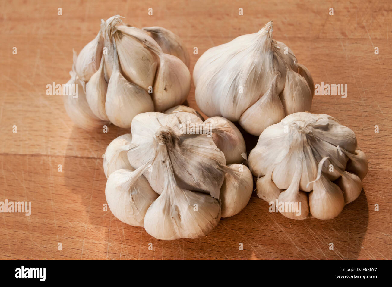 Four garlic cloves on wooden board background Stock Photo - Alamy