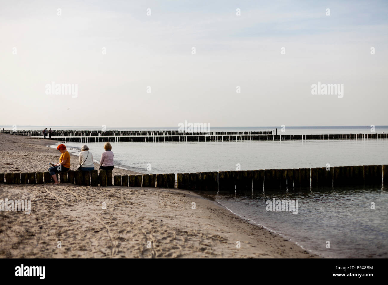 Women sitting on groynes at beach of Nienhagen, Mecklenburg-Western Pomerania, Germany Stock Photo