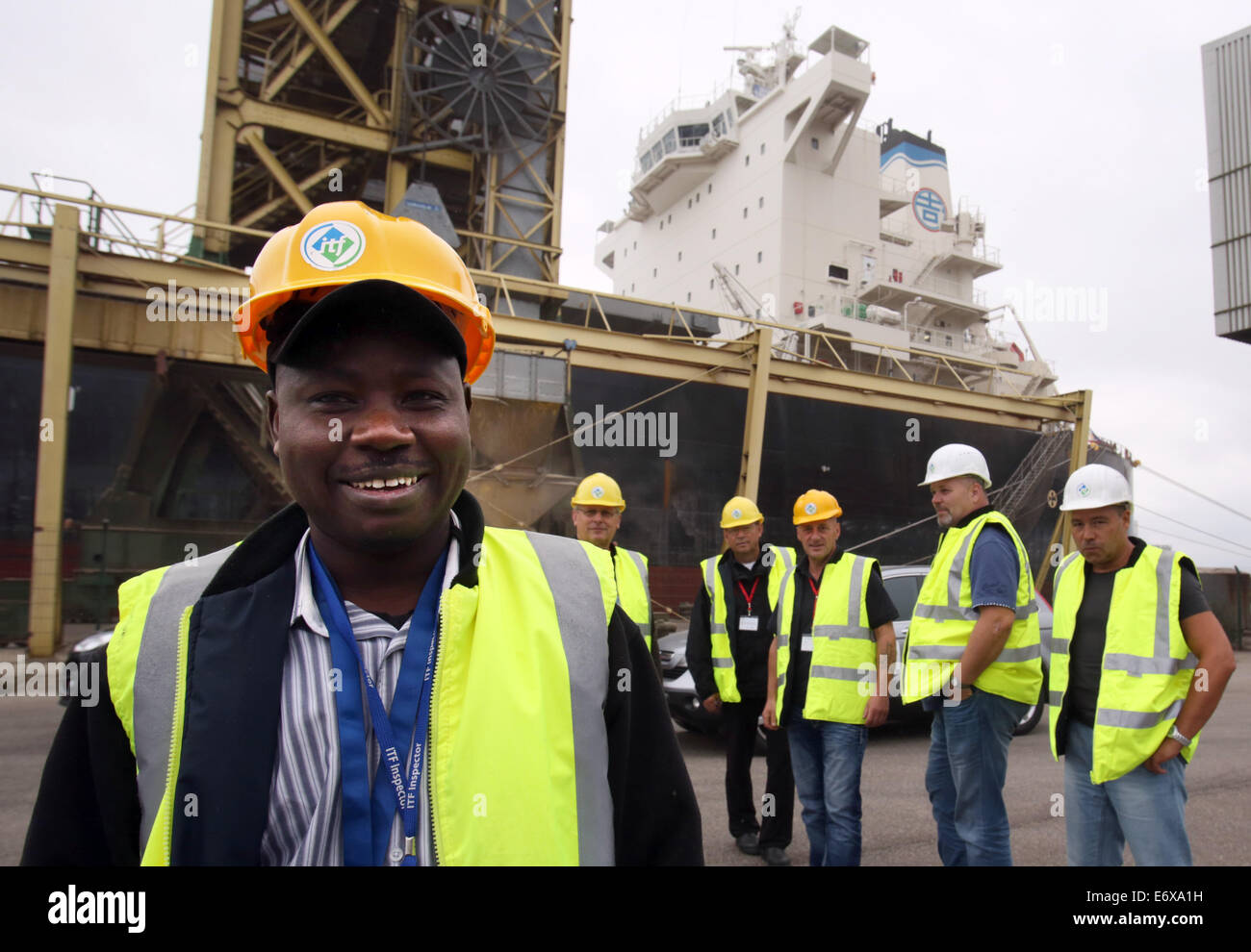 Rostock, Germany. 1st Sept, 2014. Inspector of the 'International Transport Workers' Federation (ITF)', Hamani Amadou (front) and union representatives stand in front of the grain cargo ship Mangan Trader in the seaport of Rostock, Germany, ß1 September 2014. The ITF has launched a one-week initiative around various seaports along the Batlic Sea, to inspect the living and working conditions of sailors onboard cargo vessles which sail under low-cost foreign flags. Credit:  dpa picture alliance/Alamy Live News Stock Photo