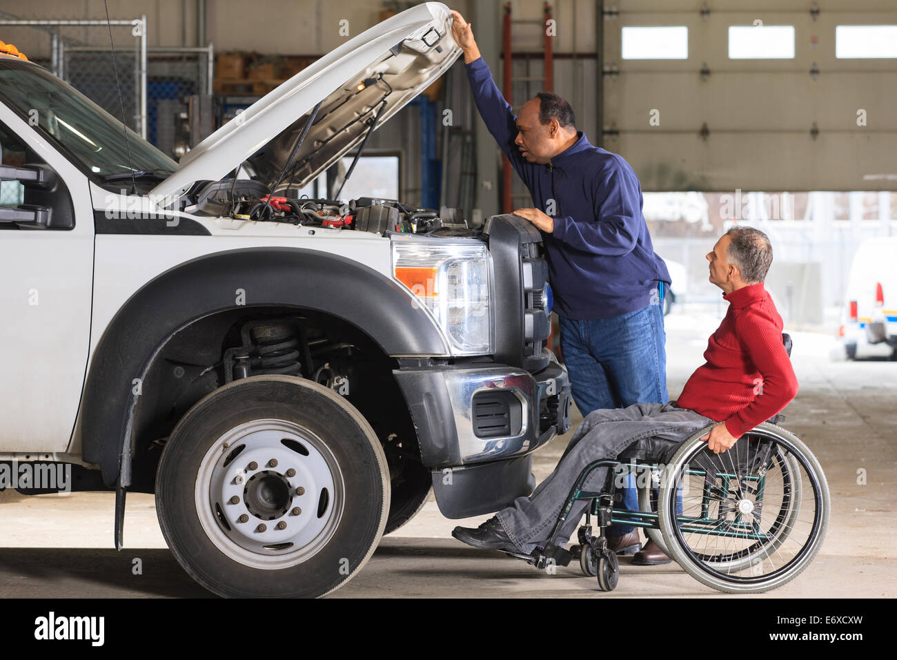 Automotive maintenance technician and supervisor with spinal cord injury in truck garage Stock Photo