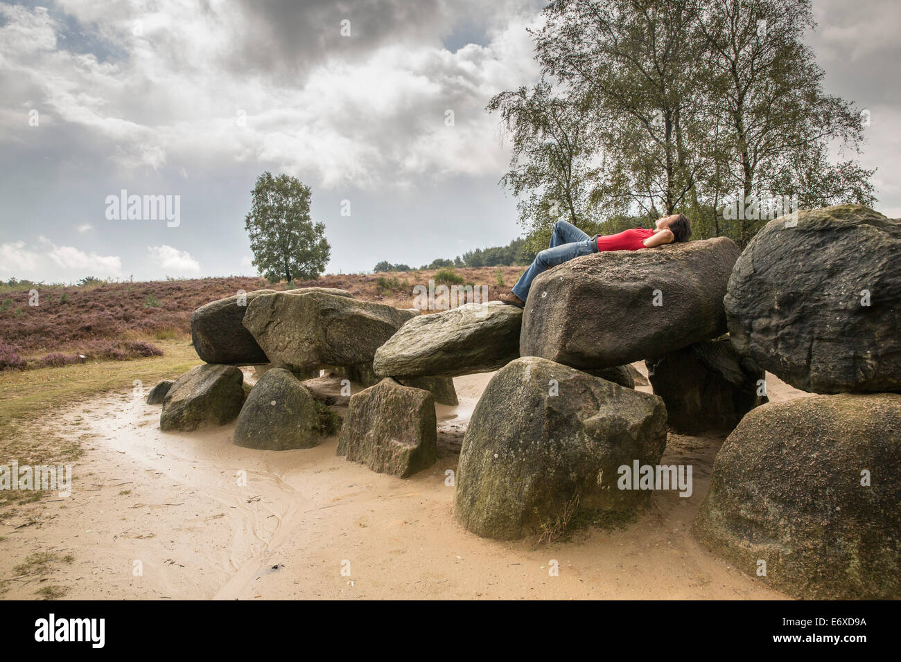 Netherlands, Havelte, Heathland  Holtingerveld Heide. Megalithic tomb called Hunebed. Number Havelterberg 54. Woman relaxes Stock Photo