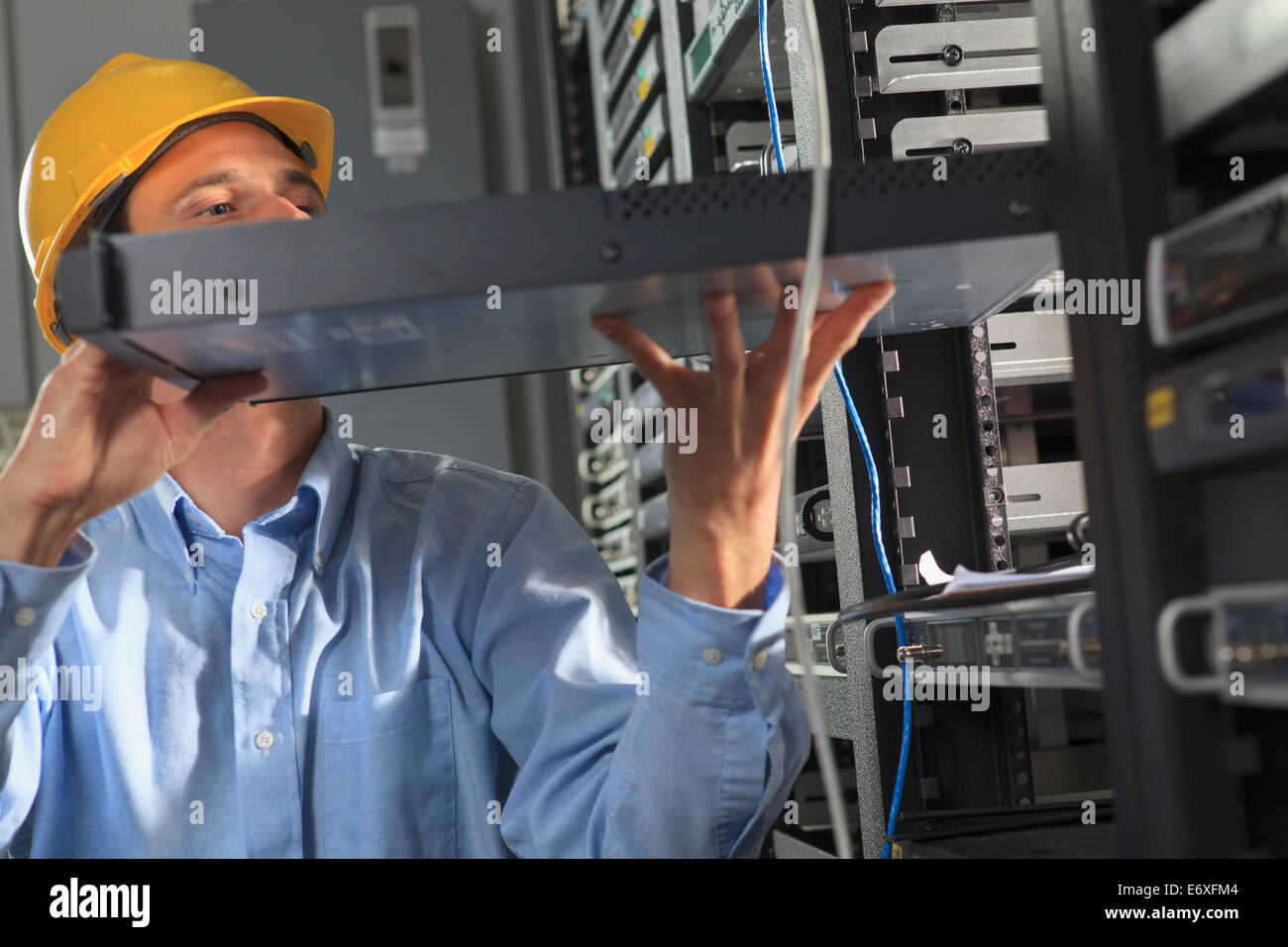 Network engineer installing cable equipment in rack Stock Photo Alamy
