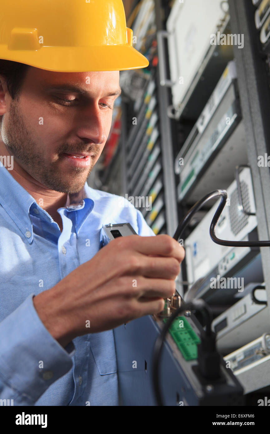 Network engineer installing cable equipment in rack Stock Photo