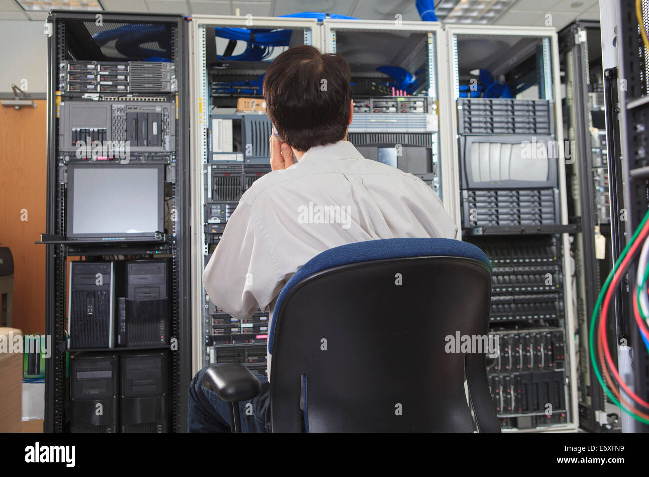 Network engineer reviewing control panels while on smart phone Stock Photo