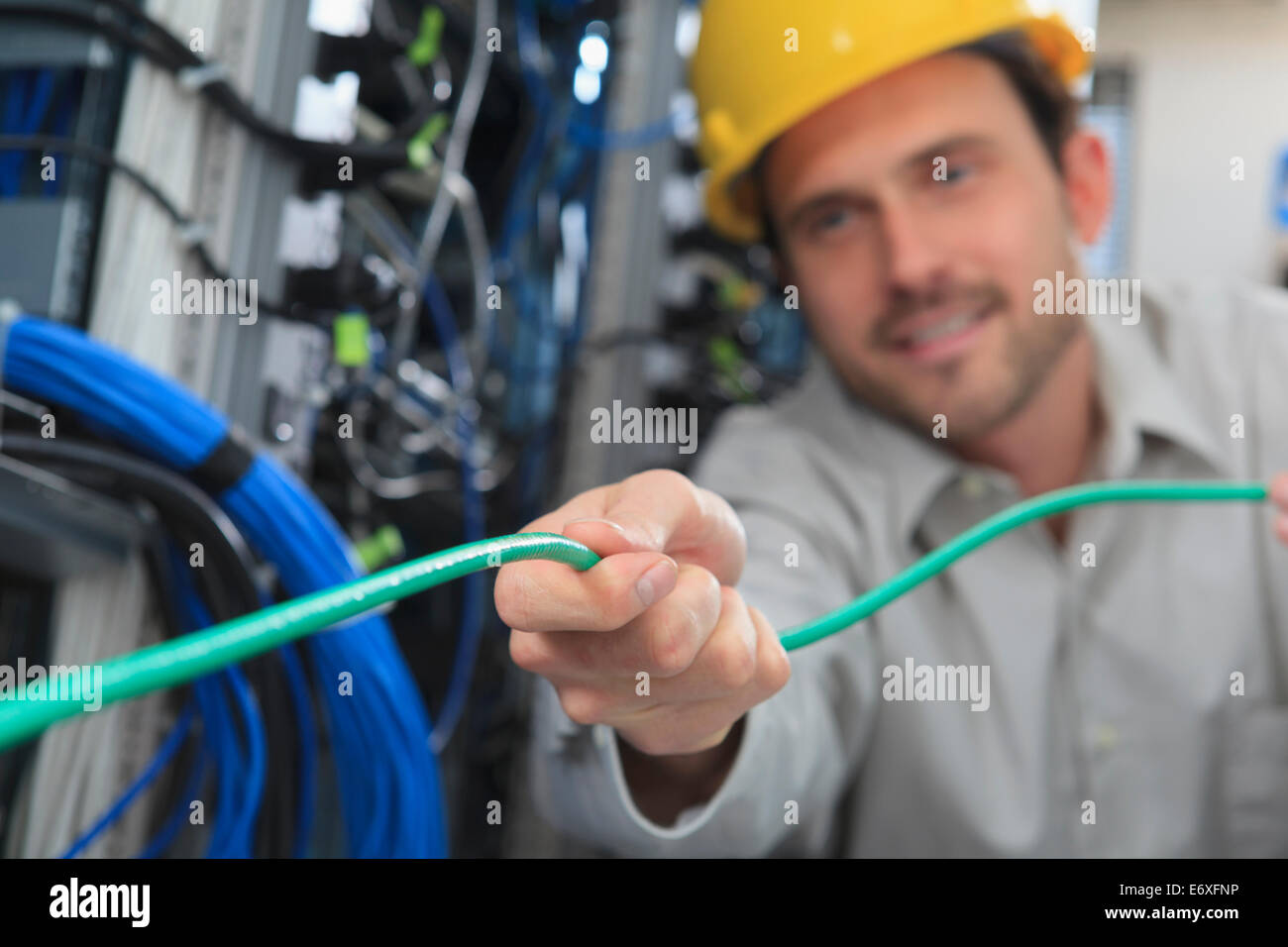 Network engineer pulling cable from reel in network data center Stock